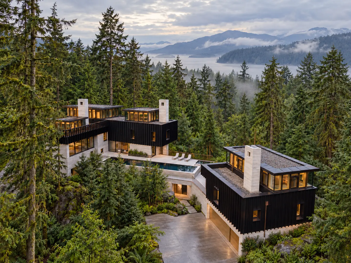 An elevated view of a residence among evergreens overlooking misty water